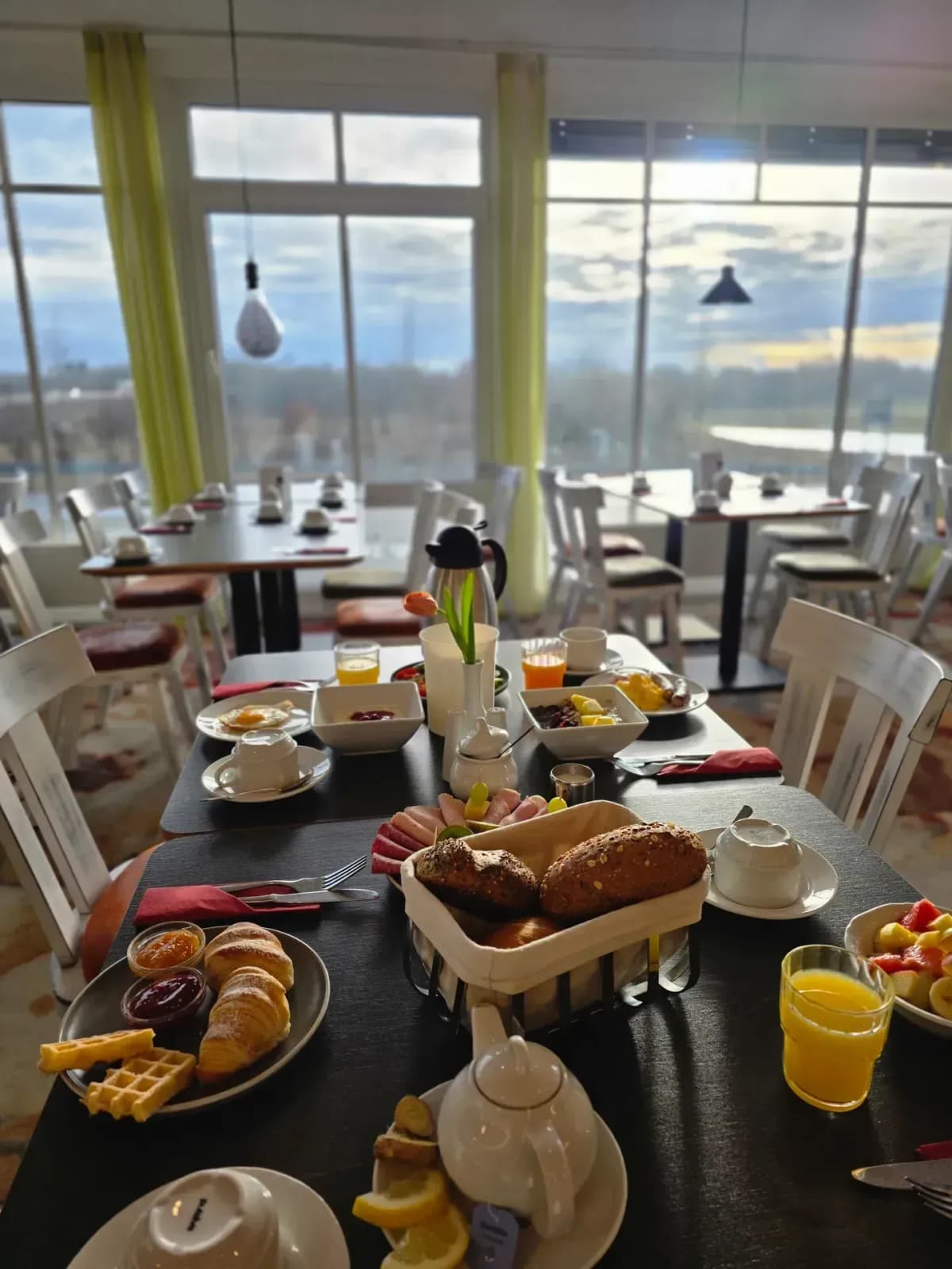 Frühstückstisch mit Brötchenkorb und Panoramablick bei Sonnenaufgang