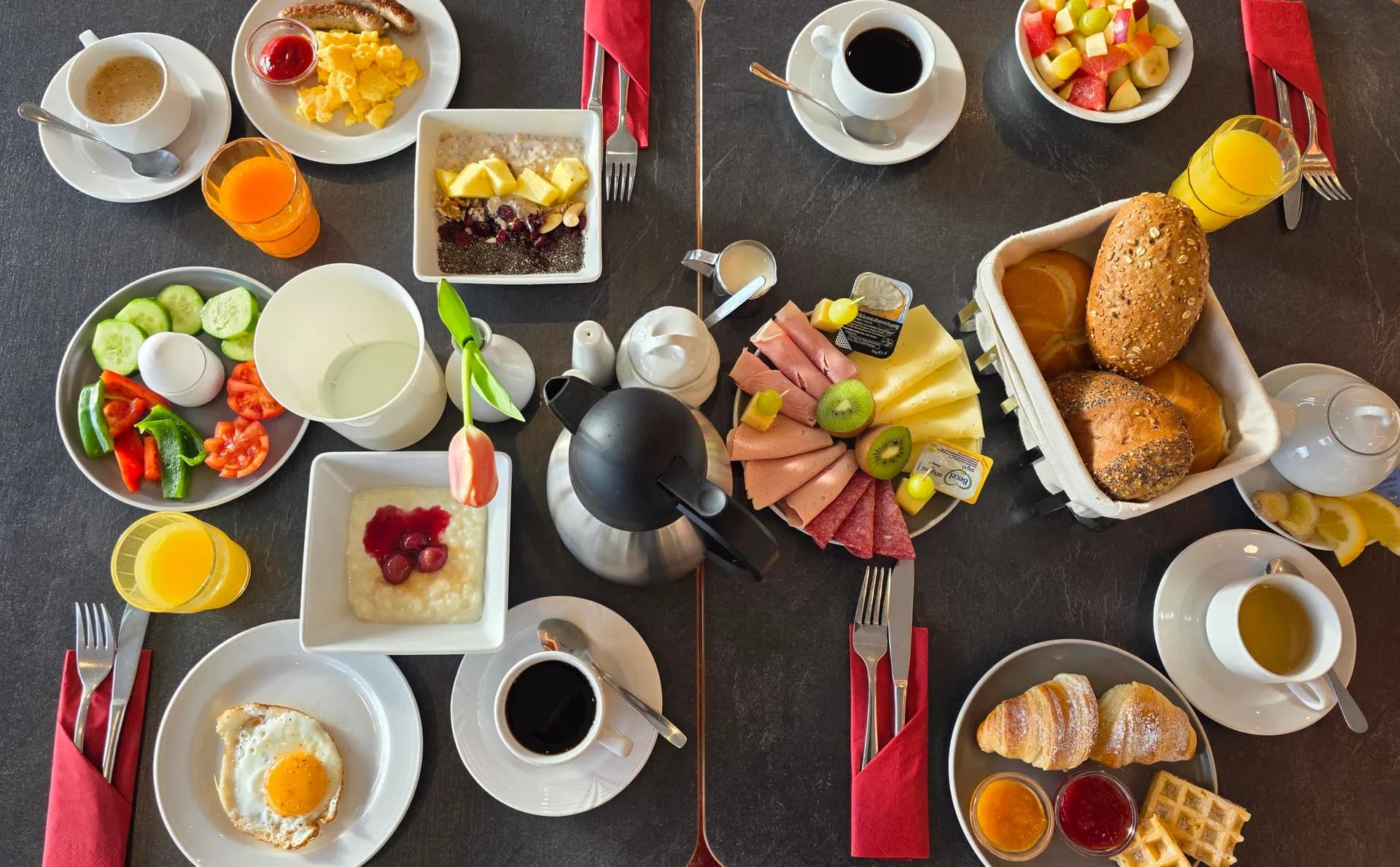 Frühstückstisch von oben – Brötchen, Croissants, Waffeln, Aufschnitt und frisches Obst im Hotel Günter